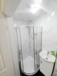 a white bathroom with a shower and a sink at Double ensuite room in Leicester