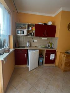 a kitchen with red cabinets and a white refrigerator at Apartmány Potůčky in Potŭčky