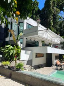 a white house with a swimming pool in front of it at Maison Ruibal in Rio de Janeiro