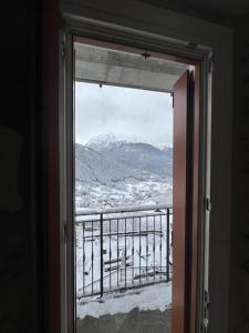 a view of a snowy mountain through a window at Trilocale con vista piste da sci in Villa Dalegno
