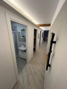 a hallway leading to a bathroom with a sink at Trilocale con vista piste da sci in Villa Dalegno