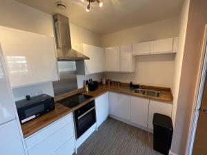 a kitchen with white cabinets and a stove top oven at Electra house in Swindon