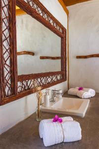 a bathroom with a sink and a mirror and towels at Casa Caroá - Chalé 1 in Japaratinga