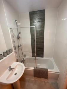 een badkamer met een douche, een wastafel en een bad bij Electra house in Swindon