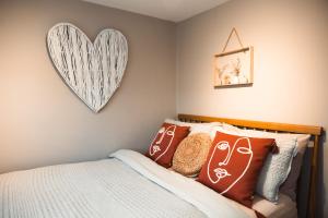 een slaapkamer met een bed met kussens en een hart aan de muur bij The Rambler's Rest Cottage, Parkgate, Wirral in Parkgate