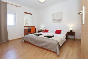 ein weißes Schlafzimmer mit einem großen Bett mit roten Kissen in der Unterkunft Holiday home Luka-sauna & jacuzzi in Privlaka