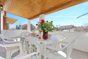 einen Tisch mit weißen Stühlen und eine Vase aus Blumen in der Unterkunft Holiday home Luka-sauna & jacuzzi in Privlaka