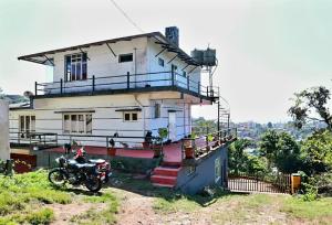 a house with a motorcycle parked in front of it at Coorg nest Home stay in Madikeri