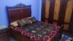 Schlafzimmer mit einem Bett mit einem Kopfteil aus Holz in der Unterkunft Air-conditioned apartment - شقة مكيفه للايجار ف ميامي in Alexandria