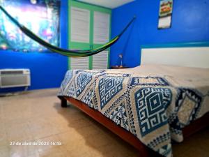 una camera con un letto con una parete blu di Confortable y colorida casa con piscina a Cancún