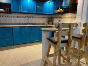 a kitchen with blue cabinets and two wooden stools at Apartamento con garaje, sin escaleras y muy bien ubicado in Palmira