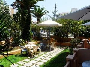 un patio con mesas, sillas y una sombrilla en Alexandros Studios & Apartments, en La Canea