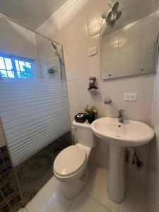 a white bathroom with a toilet and a sink at Casa Vasquez in San Felipe de Puerto Plata