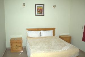 Morning Start Apartments في الأقصر: غرفة نوم مع سرير مع مواقف ليلتين وطاولتين