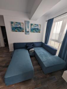 a living room with a blue couch and a window at Black Sea Overlook in Mamaia Sat/Năvodari