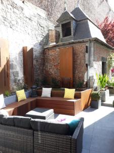 a patio with a couch and chairs in front of a brick building at Couque cuivrée II in Dinant