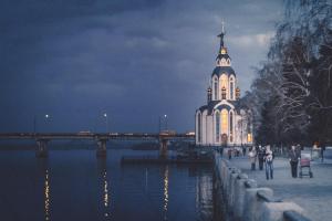 a building with a clock tower next to a river at Европейская 17 Мост сити Центр in Dnipro