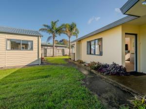 a house with a yard next to a house at Hosts on the Coast - Seas the Day in Cooks Beach