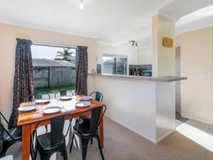 a kitchen and dining room with a table and chairs at Hosts on the Coast - Seas the Day in Cooks Beach