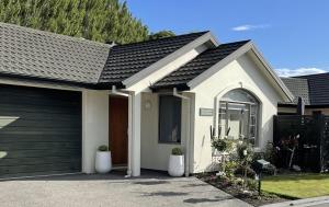 una pequeña casa blanca con garaje en Villa55, en Christchurch