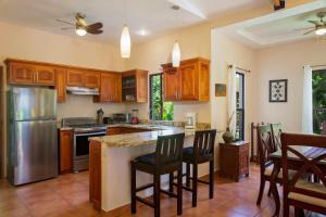 a kitchen with wooden cabinets and a kitchen island with bar stools at Zen Casita near Playa Colorado! in Tola