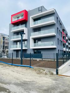 een grijs appartementencomplex met een rood dak bij Rozmarynowy in Opole