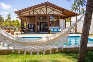 a hammock in front of a house with a pool at Casa Caroá - Chalé 1 in Japaratinga