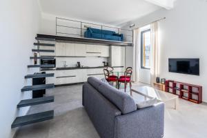 een woonkamer met een grijze bank en een keuken bij Boccadasse Chic Urban Retreat in Genua
