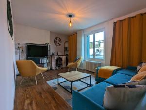 un soggiorno con divano blu e TV di Grande maison avec extérieur, jacuzzi et billard a Vierzon