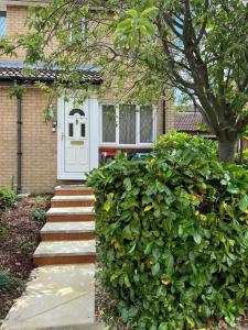 uma casa com uma porta branca e um arbusto em MK City Center House* 2 bed em Milton Keynes