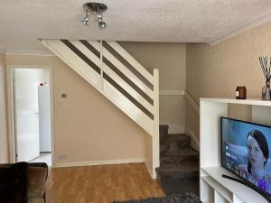 a living room with a staircase and a flat screen tv at MK City Center House* 2 bed in Milton Keynes