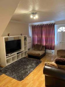 uma sala de estar com uma televisão de ecrã plano e um sofá em MK City Center House* 2 bed em Milton Keynes