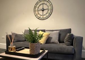 a living room with a couch and a clock on the wall at Trendy West End Apartment, Glasgow in Glasgow