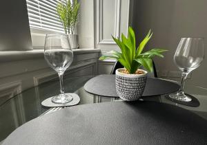 - une table avec deux verres à vin et une plante dans l'établissement Trendy West End Apartment, Glasgow, à Glasgow