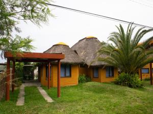 a yellow house with a thatched roof at Coco Loco Lodge in La Paloma
