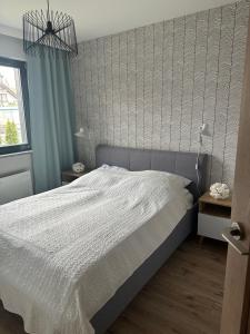 a bedroom with a bed with a white comforter at Apartament w Nautikka Resort Krynica Morska in Krynica Morska