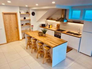a kitchen with a wooden counter and stools at Penagoda Beach House in Espinho