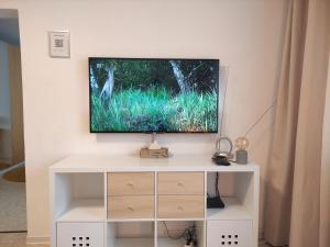 un centro de entretenimiento blanco con TV en la pared en Apartment E - feel good, en Leipzig