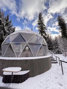 a dome building with a bench and a table in the snow at SlavskoGlamping in Slavske