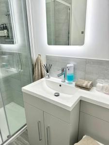 a white bathroom with a sink and a shower at The Modern Smart Home in Great Warley Street +2 photos