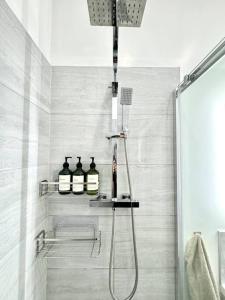 a bathroom with a shower with three bottles on a shelf at The Modern Smart Home in Great Warley Street