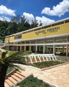 un gran edificio amarillo con una palmera delante de él en Casarão ao lado do Hotel Majestic en Águas de Lindóia