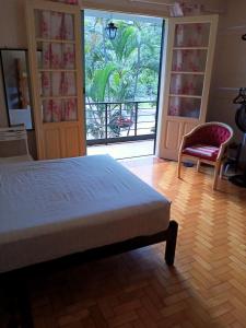 - une chambre avec un lit, une chaise et une fenêtre dans l'établissement Casarão ao lado do Hotel Majestic, à Águas de Lindóia