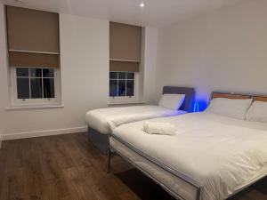 two beds in a room with two windows at Black Frairs Apartments in London