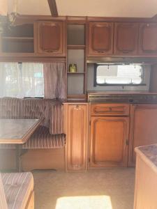 a kitchen with wooden cabinets and a table in an rv at Camping Rogowo in Mrzeżyno