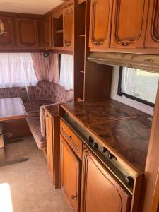 a kitchen with wooden cabinets and a stove in an rv at Camping Rogowo in Mrzeżyno