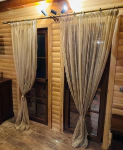 two curtains in a room with wooden walls at Planinska kuća Mali Raj in Mrkonjić Grad
