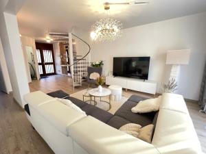 a living room with a white couch and a tv at Superbe villa à 2 km centre ville de Colmar in Horbourg