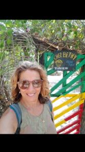 Una donna con gli occhiali da sole davanti a un cartello di Chez Bethy Jungle et Océan ad Abémé