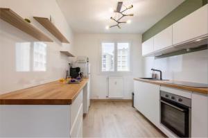 a kitchen with white cabinets and a wooden counter top at Logement Autour de Moi * * * * * in Chambéry
